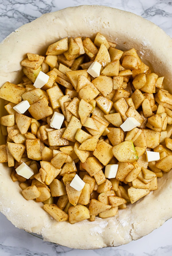 Unbaked pie filling dotted with butter in pie plate.