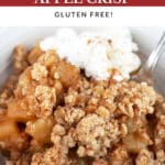 Apple crisp with whipped cream in white bowl with fork.