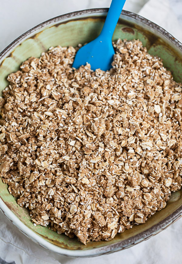 Oatmeal cinnamon streusel in ceramic bowl with blue spatula.