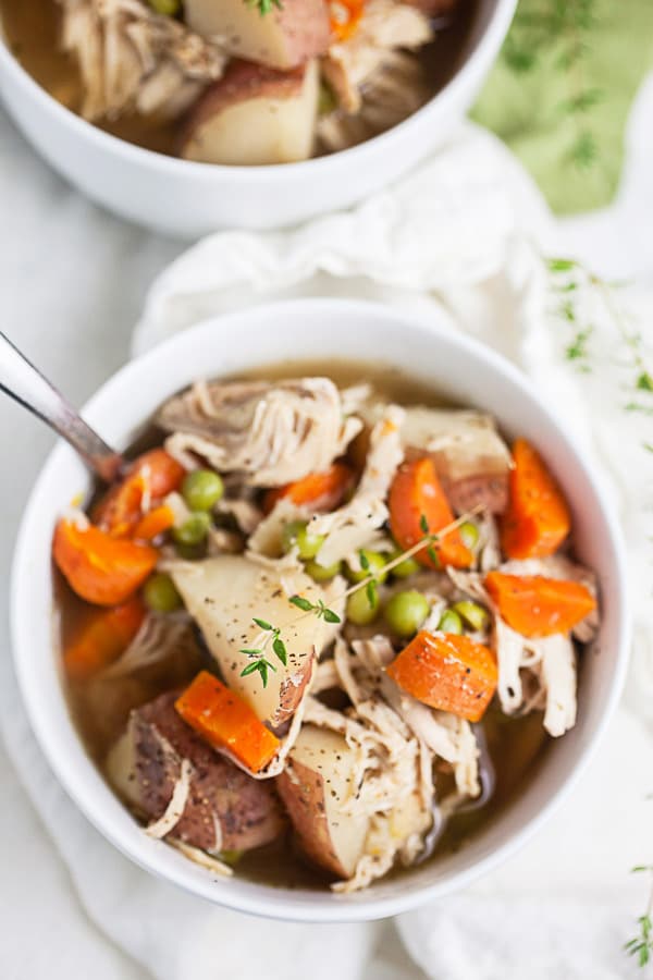 Chicken potato soup in small white bowls with thyme.