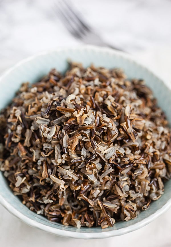 Cooked wild rice in blue serving bowl.