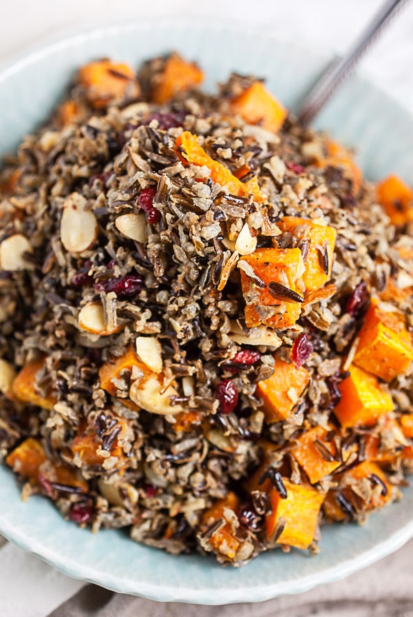 Wild rice salad with butternut squash, almonds, and cranberries in blue serving bowl.