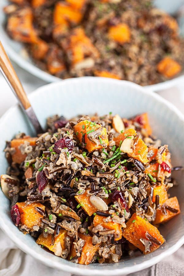 Harvest wild rice salad with butternut squash in blue bowl with fork.