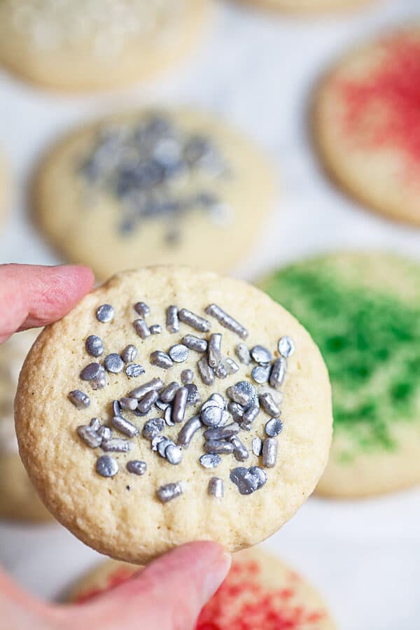 Hand holding crispy sugar cookie with sprinkles.