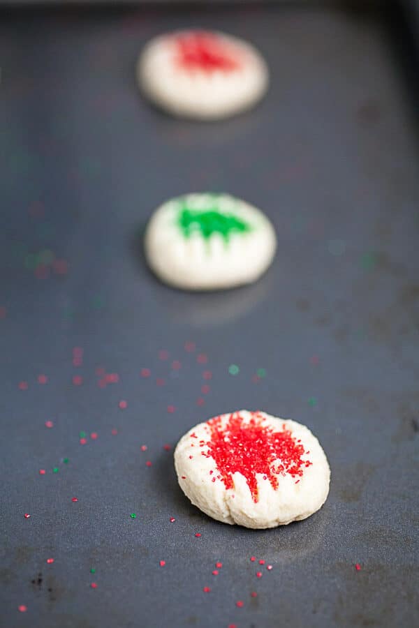 Unbaked cookies with sprinkles on metal baking sheet.