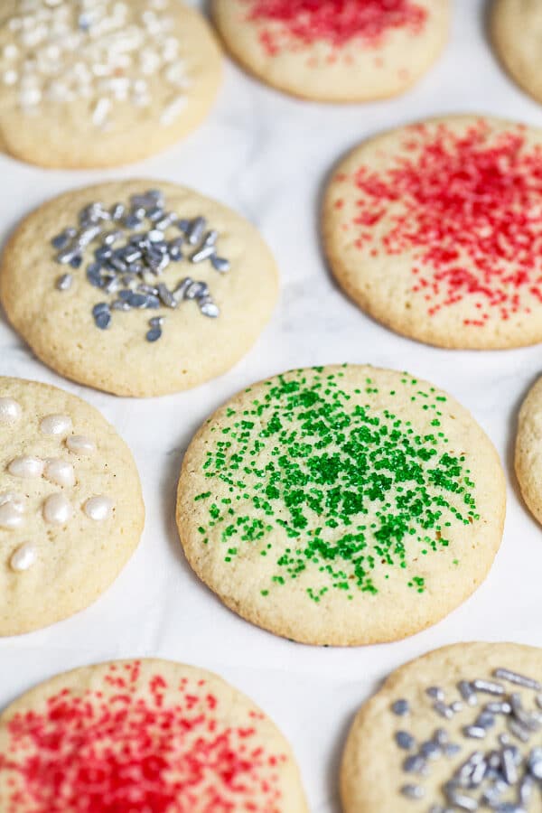 Baked old fashioned sugar cookies with assorted sprinkles on white surface.