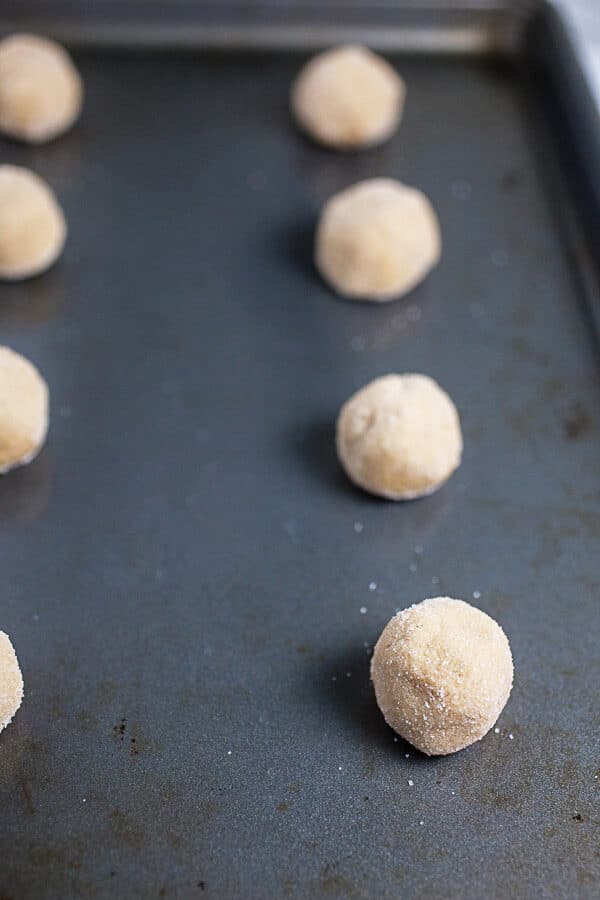 Unbaked cookie dough balls on metal baking sheet.