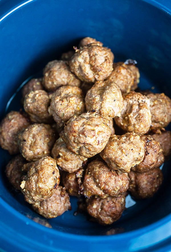 Baked turkey meatballs stacked in blue crockpot.