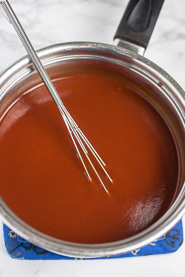 BBQ sauce mixture in sauce pan with whisk.