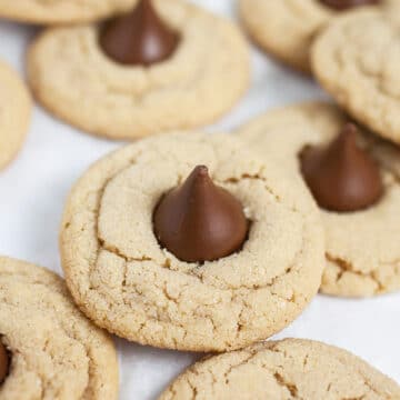 Classic peanut butter blossom cookies on white surface.