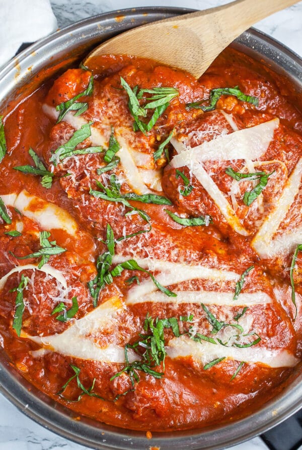 Cooked chicken Parmesan with marinara sauce in skillet.