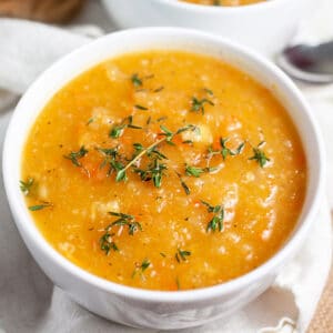 Winter root vegetable soup in small white bowl garnished with thyme.