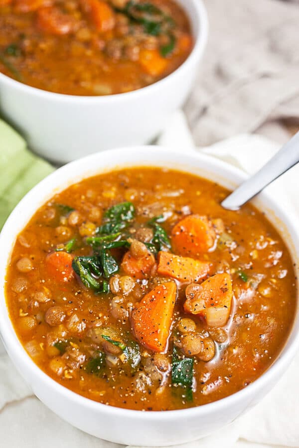 Lentil soup with carrots and spinach in white bowls.