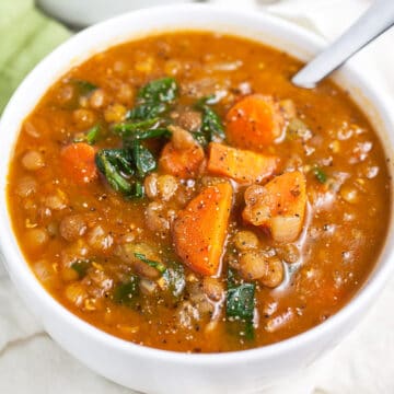 Instant pot lentil soup in white bowl with spoon.