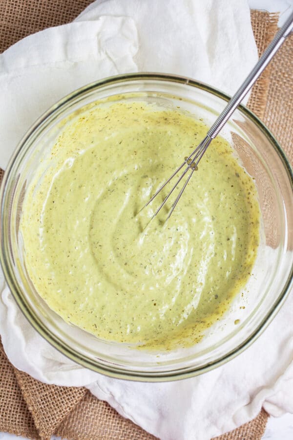 Lemon basil pesto mayo in small glass bowl with whisk.