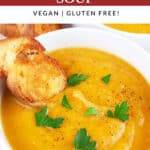 Winter root vegetable soup in white bowl garnished with parsley and crostini.