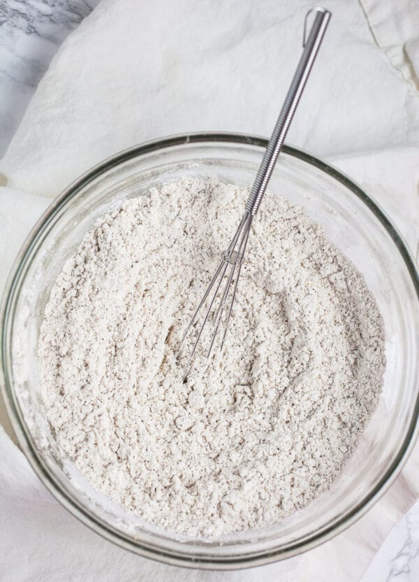 Spiced flour mixture in small glass bowl with whisk.