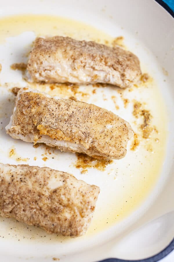 Fish filets pan seared in white cast iron skillet.