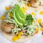 Fish tacos with cilantro lime slaw, bell peppers, avocado, and cilantro.