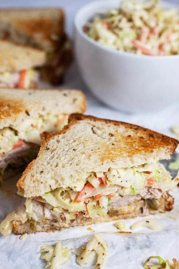 Turkey Rachel sandwich with bowl of coleslaw cut in half.