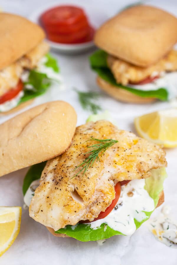 Pan fried walleye sandwiches on buns with tartar sauce, lettuce, tomatoes, and fresh dill.