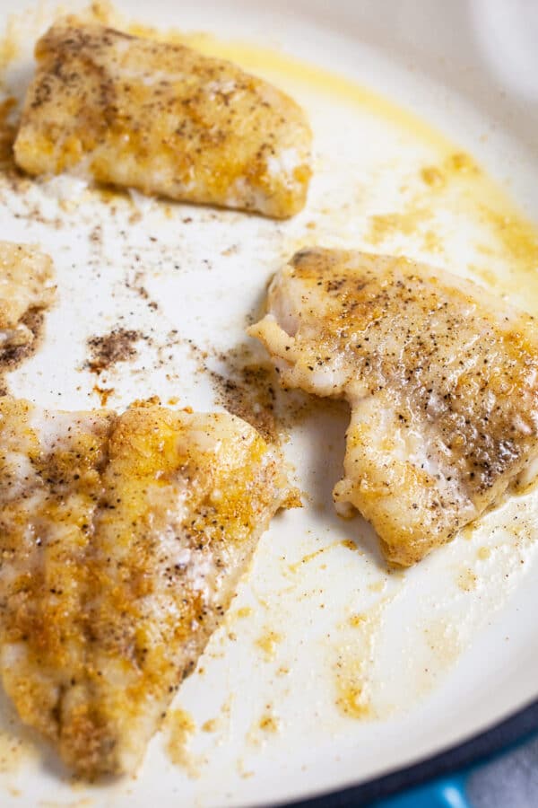 Walleye fish filets sautéed in white cast iron skillet.