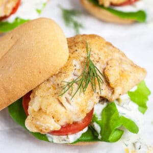 Pan fried walleye sandwich on bun with tartar sauce, lettuce, tomatoes, and fresh dill.