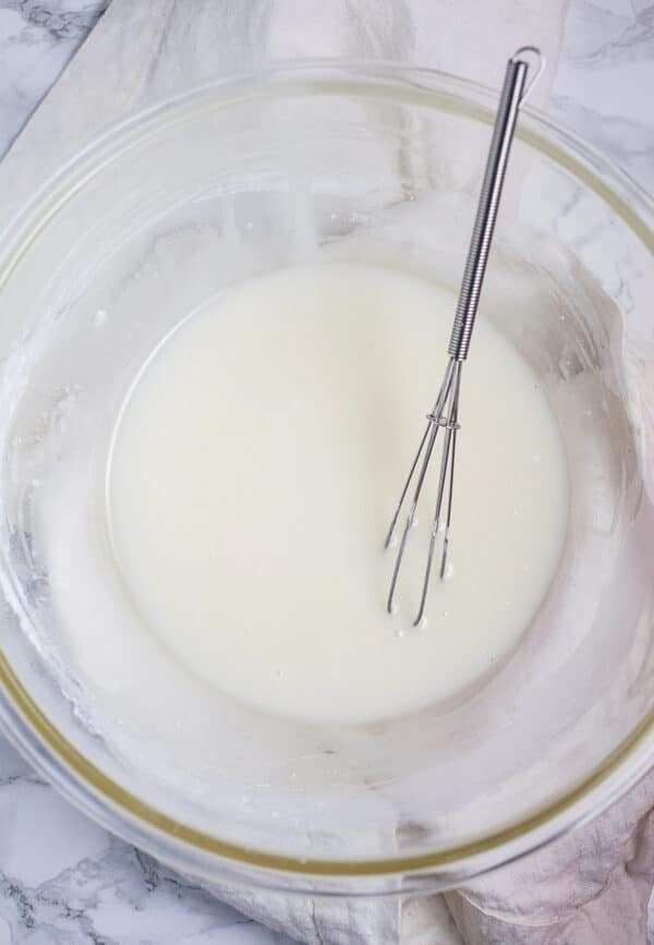 Lemon glaze in small glass bowl with whisk.