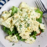Lemon dill egg salad on bread with lettuce on small white plate.