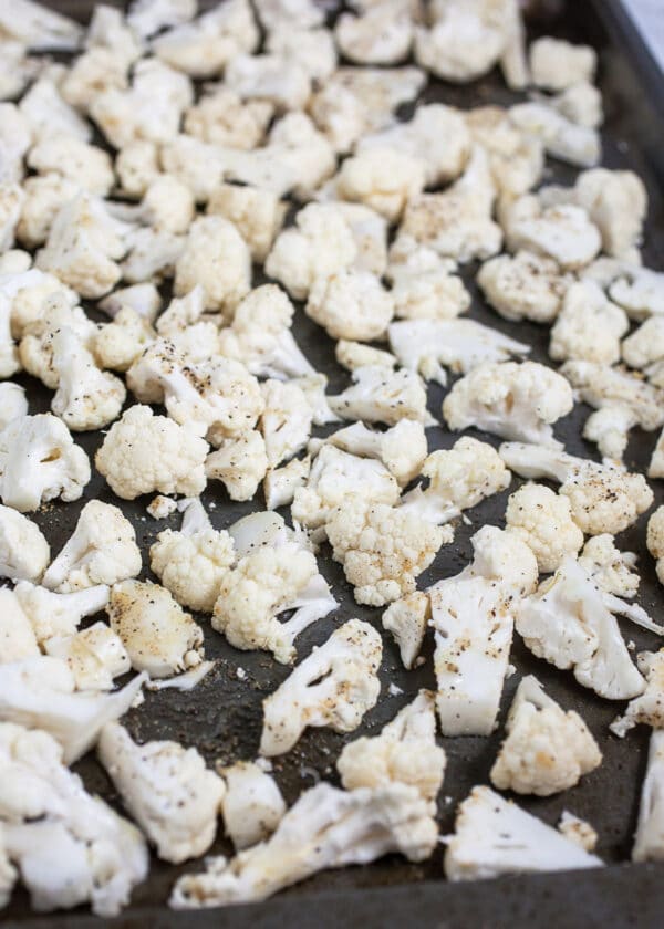 Uncooked cauliflower florets on metal baking sheet.