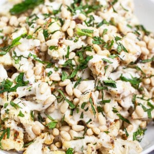 Mediterranean lemon tahini roasted cauliflower in white bowl with mint.