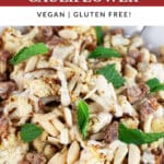 Mediterranean roasted cauliflower with tahini sauce, slivered almonds, chopped dates, and fresh mint in white bowl with fork.