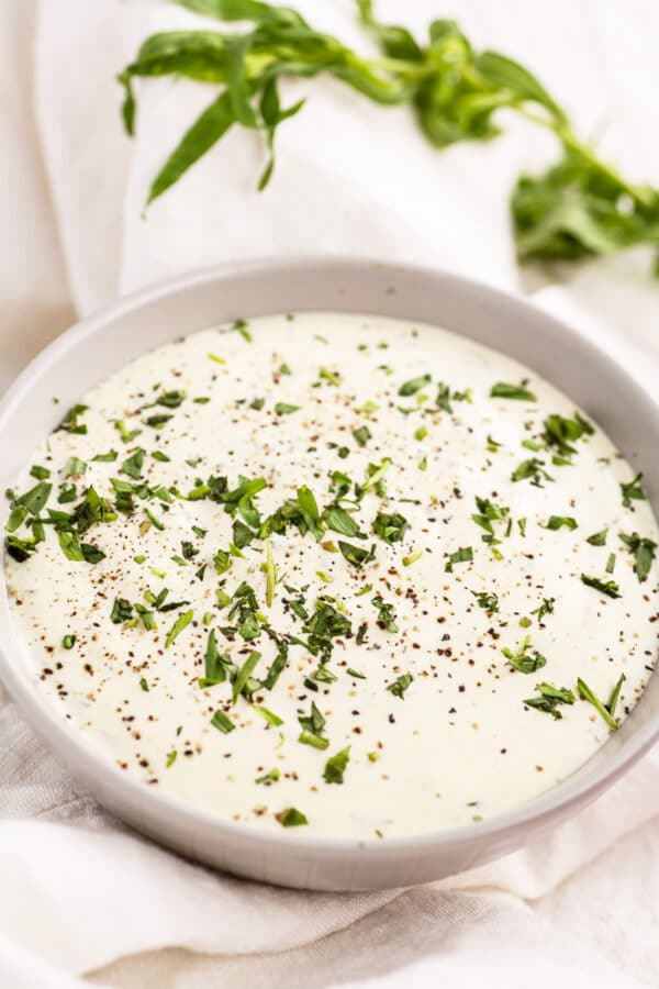 Creamy lemon mustard tarragon sauce with minced tarragon in small bowl.