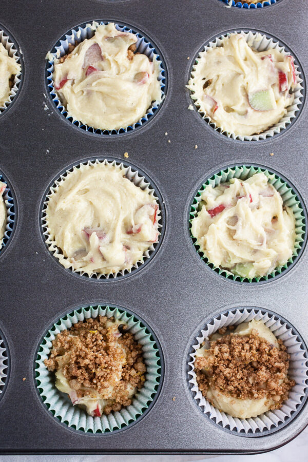 Rhubarb muffin batter with streusel in metal muffin tin.