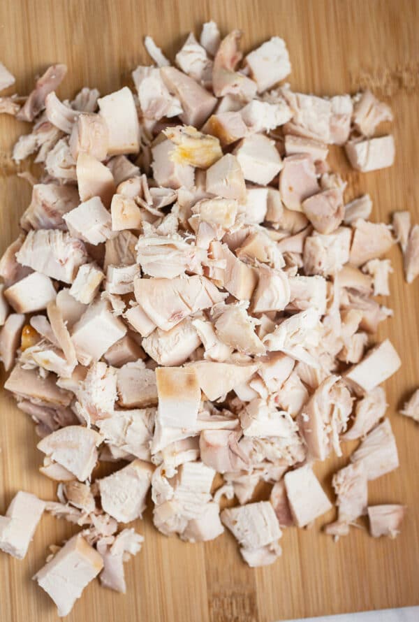 Diced rotisserie chicken on wooden cutting board.