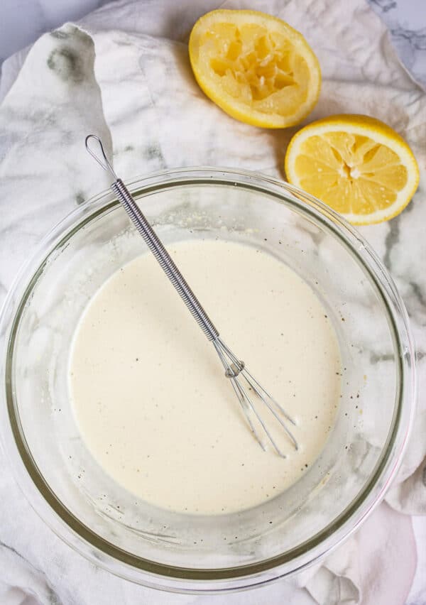 Lemon mayo dressing in small glass bowl with whisk.