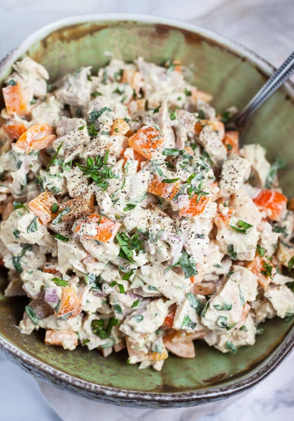 Lemon basil chicken salad in green ceramic bowl with spoon.