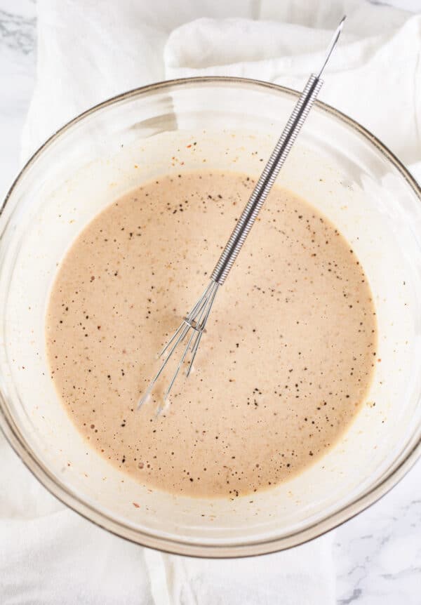 Chipotle mayo dressing in small glass bowl with whisk.