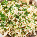 Southwest coleslaw with chipotle lime dressing in ceramic bowl topped with minced cilantro.