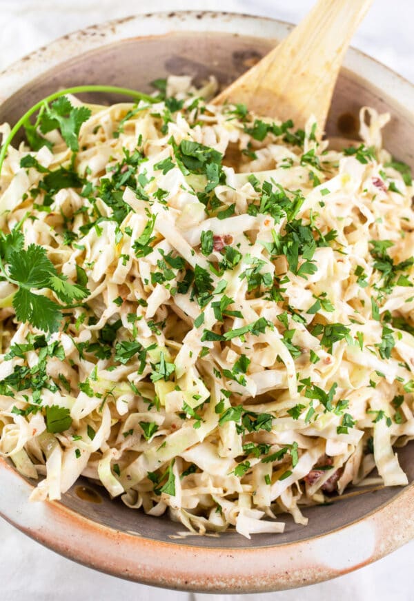 Southwest coleslaw with chipotle lime dressing in ceramic bowl topped with minced cilantro.
