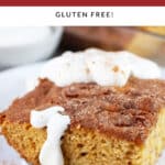Piece of gluten free rhubarb cake topped with whipped cream on white plate with fork.