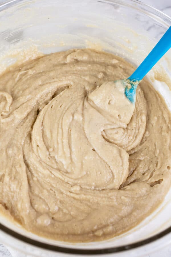 Cake batter in large glass bowl with blue spatula.