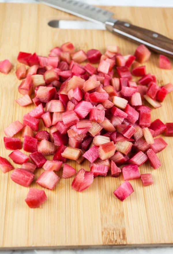 Chopped rhubarb on wooden cutting board with knife.