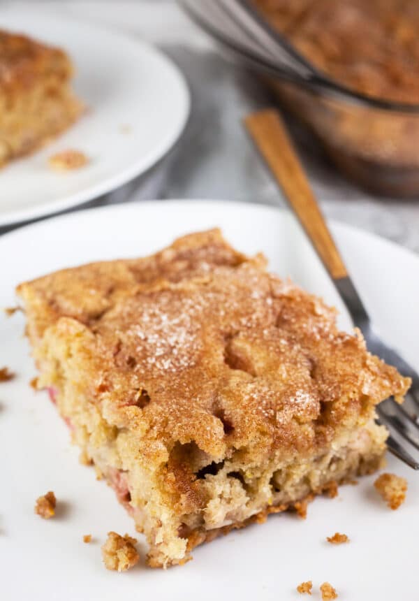 Gluten free buttermilk rhubarb cake on small white plate with fork.