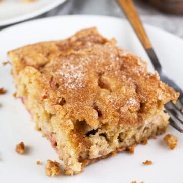 Gluten free buttermilk rhubarb cake on small white plate with fork.