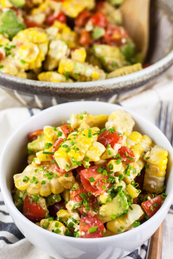 Grilled corn, tomato, and avocado salad in white bowl.