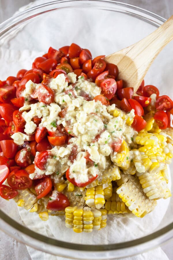 Corn, tomatoes, and feta dressing in large glass bowl.