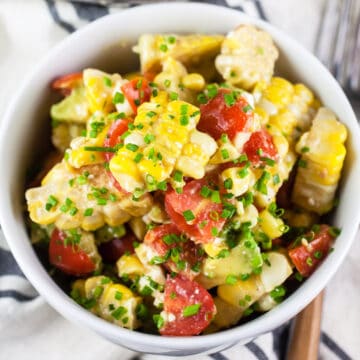 Grilled corn, tomato, and avocado salad in small white bowl.