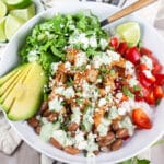 Mexican shrimp rice bowl with red peppers, lettuce, avocado, and cilantro lime cream sauce with queso fresco cheese.