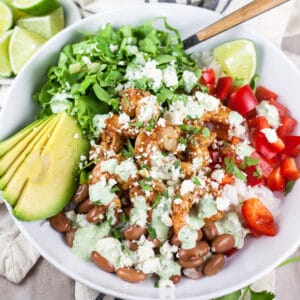 Mexican shrimp rice bowl with red peppers, lettuce, avocado, and cilantro lime cream sauce with queso fresco cheese.